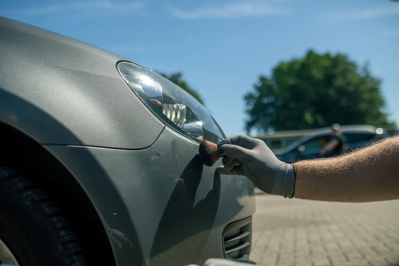 Kontaktpuder auf dem Kotflügel eines grauen Autos macht feine Risse im Lack sichtbar